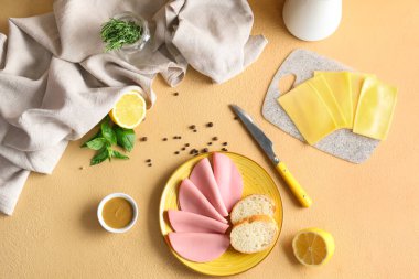 Bej arka planda kaynamış sosis, ekmek, peynir ve hardal sosu dilimli tabak.