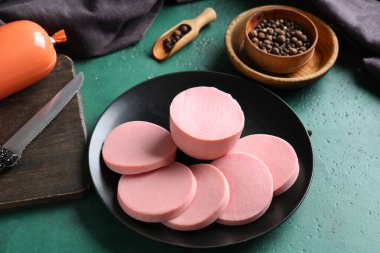 Lezzetli kaynamış sosis dilimleri ve grunge yeşil arka planda biberli mısır.