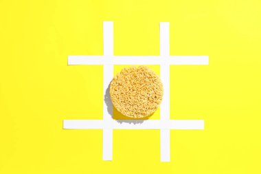 Çiğ erişte ve sarı arkaplanda yapıştırıcı banttan yapılmış ızgara.