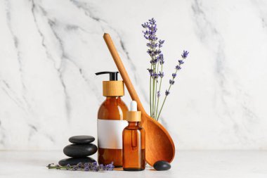 Spa taşları, ahşap kaşık, lavanta şişeleri mermer arka planda gerekli yağ ve çiçekler