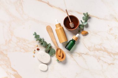 Ahşap kaşık, fındık ve okaliptüs şişeleri mermer arka planda gerekli yağ
