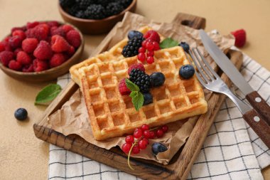 Farklı taze böğürtlenler ve kahverengi arka planda naneli tatlı Belçika waffleları.