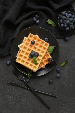 Bir tabak taze yaban mersinli Belçika waffle 'ı ve siyah arkaplanda nane şekeri