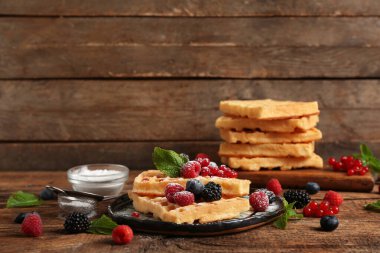 Farklı taze meyveli Belçika waffle tabağı ve ahşap zemin üzerinde nane.
