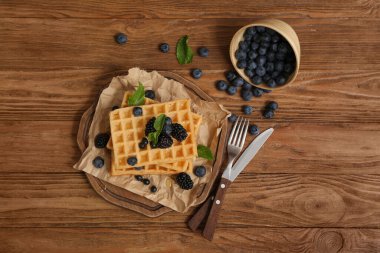 Taze yaban mersini, böğürtlen ve ahşap zemin üzerinde nane şekerli Belçika waffleları.