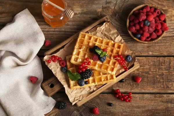 Farklı taze böğürtlen ve ahşap arka planda bal dolu Belçika waffle 'ları.