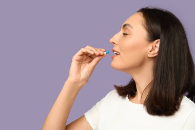 Pembe arka planda hap alan güzel bir genç kadın. Yakın plan.