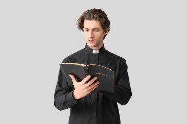 Genç rahip karanlık arka planda kutsal kitapla dua ediyor.