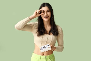 Yeşil arka planda bir kutu lezzetli çikolata şekeri olan genç bir kadın.