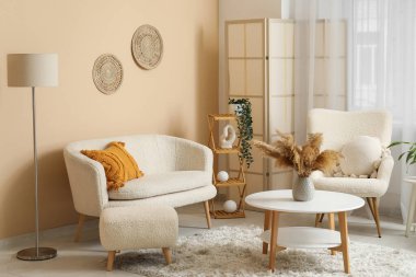 Oturma odasının içinde rahat bir kanepe, koltuk ve kahve masası.