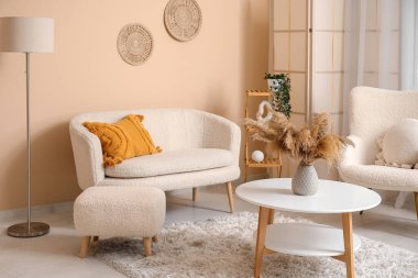 Oturma odasının içinde rahat bir kanepe, koltuk ve kahve masası.