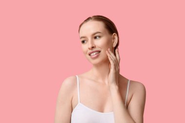 Pembe arka planda sağlıklı ciltli güzel, genç ve mutlu bir kadın.