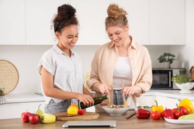 Genç kadınlar mutfakta salata yapıyor.