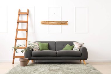 Oturma odasında rahat bir kanepe, merdiven ve dekoratif zeytin ağacı var.