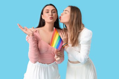 LGBT bayrağıyla mavi arka planda öpüşen güzel lezbiyen çift.