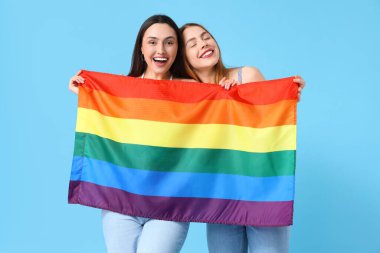Mavi arka planda LGBT bayrağı olan güzel bir lezbiyen çift.