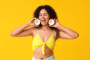 Sarı arka planda taze hindistancevizi olan güzel Afro-Amerikalı kadın.