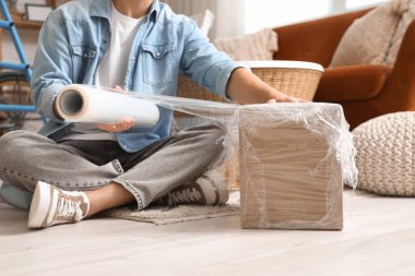 Genç adam evde streç film ile paketleme kutusu, yakın plan.