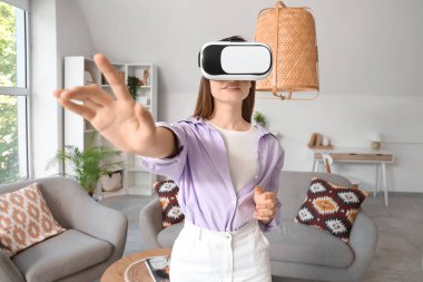 Evde VR gözlük takan genç bir kadın.