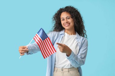 Mavi arka planda Amerikan bayrağı olan mutlu Afro-Amerikan kadın.