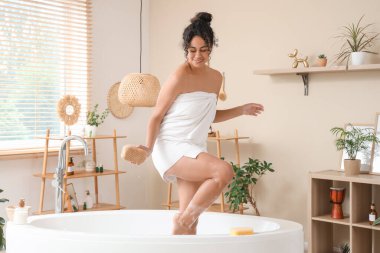 Güzel, genç, mutlu, Afro-Amerikan bir kadın. Evde sünger ve sabun köpüğüyle banyo yapıyor.