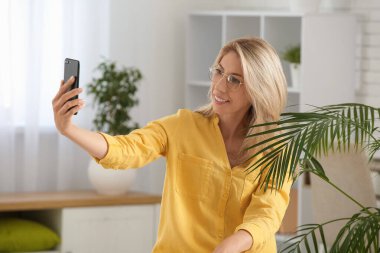 Güzel, olgun, mutlu bir kadının portresi evde selfie çekiyor.