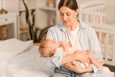 Anne ve küçük bebeği yatak odasında oturuyor.