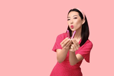 Pembe arka planda farklı rujları olan güzel bir Asyalı kadın.