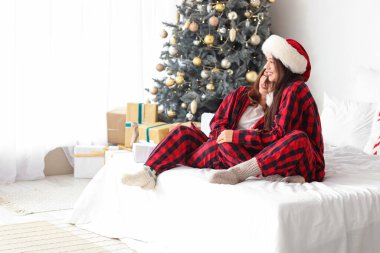 Genç lezbiyen çift Noel arifesinde yatak odasında sarılıyorlar.