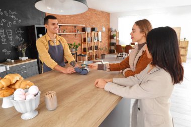 Kahve dükkanında ziyaretçilerden para alan erkek barmen.