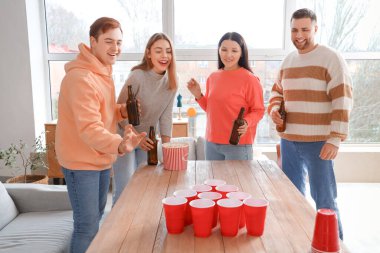 Bir grup genç arkadaş evde bira pong oynuyor.