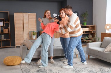 Arkadaşlarıyla birlikte evde VR gözlüğü takan genç bir kadın.