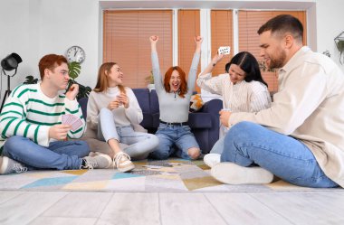 Evde kart oynayan bir grup genç arkadaş.