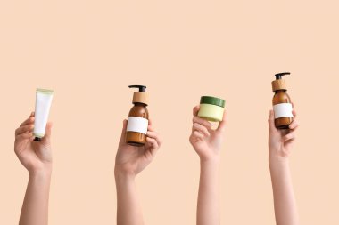 Bej arka planda farklı kozmetik ürünleri tutan kadınlar