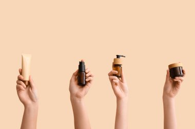 Bej arka planda farklı kozmetik ürünleri tutan kadınlar