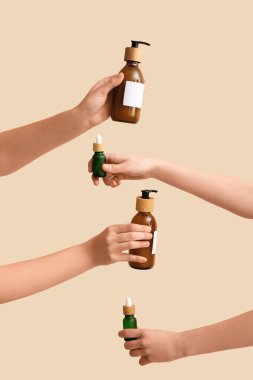 Bej arka planda farklı kozmetik ürünleri olan kadın elleri