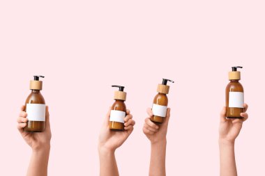 Pembe arka planda kozmetik ürünleri olan kadın elleri