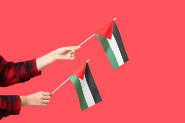 Kızıl arka planda Filistin bayrakları olan kadın eller