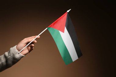 Karanlık arka planda Filistin bayrağı taşıyan bir kadın el.