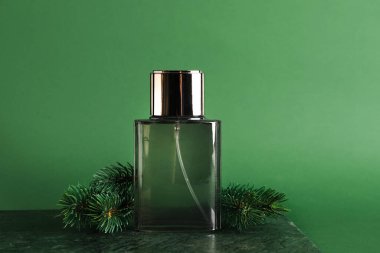 Bir şişe parfüm ve yeşil arka planda köknar dalları.