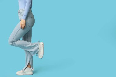 Mavi arka planda şık kotlu genç kadın.