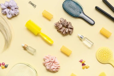 Sarı arka planda saç fırçaları, kozmetik ürünler şişeleri ve ipek tokalar.