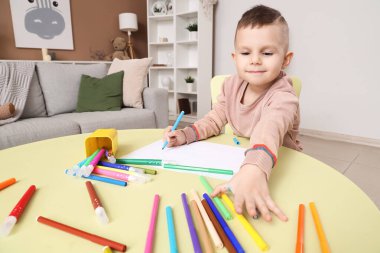 Masada keçeli kalemlerle çizen komik küçük çocuk.
