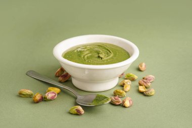 Fıstık ezmeli kase ve yeşil arka planda kaşık.