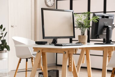 Modern desk with computer monitors in light office