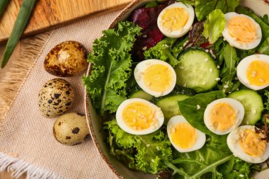 Kaynamış bıldırcın yumurtası ve sebzeli bir kase lezzetli salata, yakın plan.