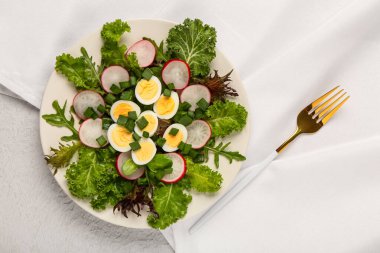 Bir tabak taze sebzeli lezzetli salata ve arka planda kaynamış bıldırcın yumurtası.