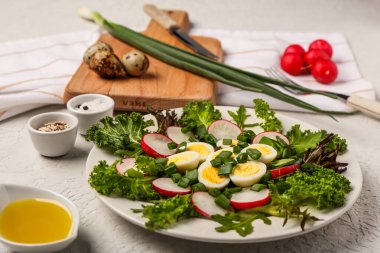 Kaynamış bıldırcın yumurtası ve hafif arkaplanda malzemelerle taze salata.