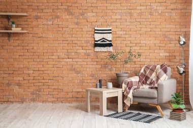 Interior of living room with grey armchair, table and lamp