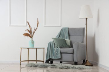 Oturma odasında sehpası ve lambası olan şık bir koltuk.